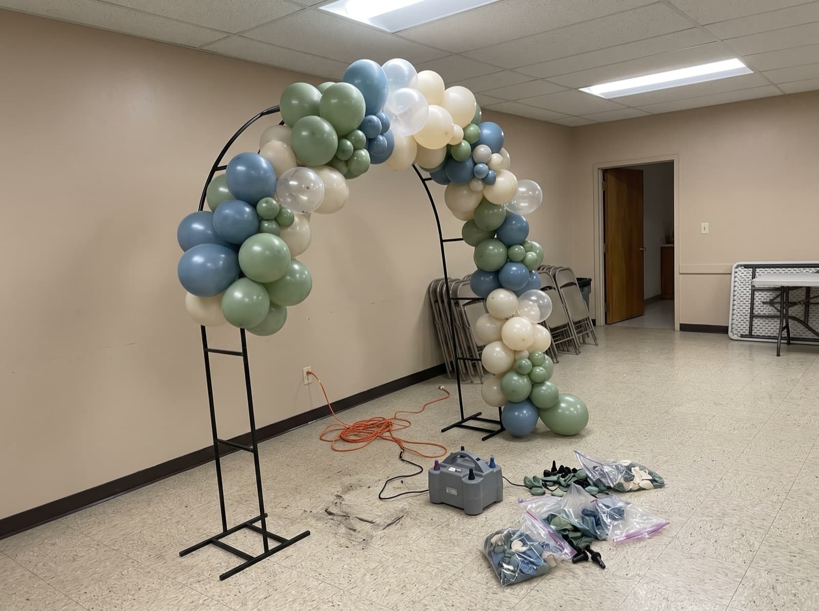 Organic balloon garland half-built on an arch frame before an event