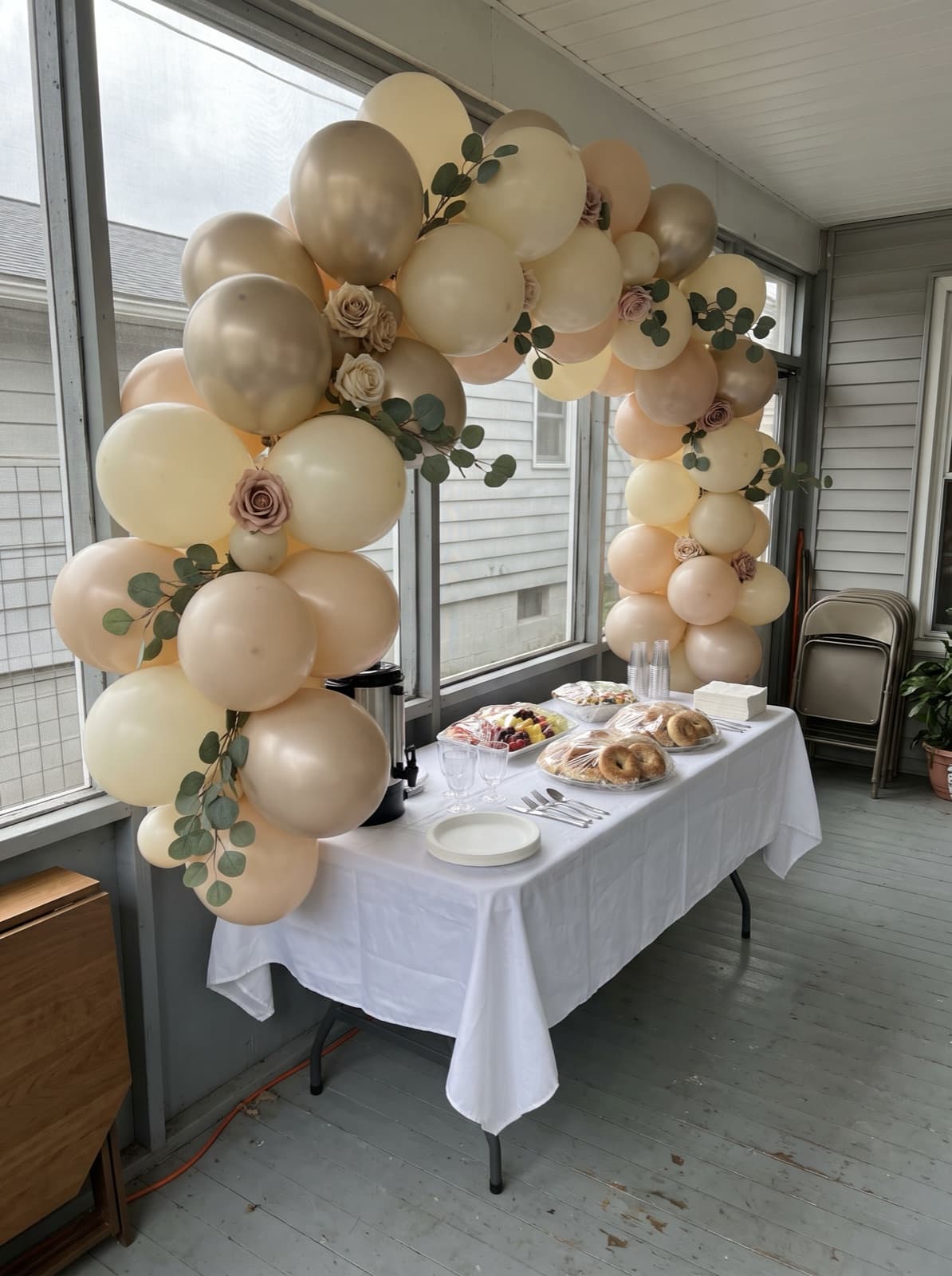 Floral balloon arch with greenery over a bridal shower brunch table