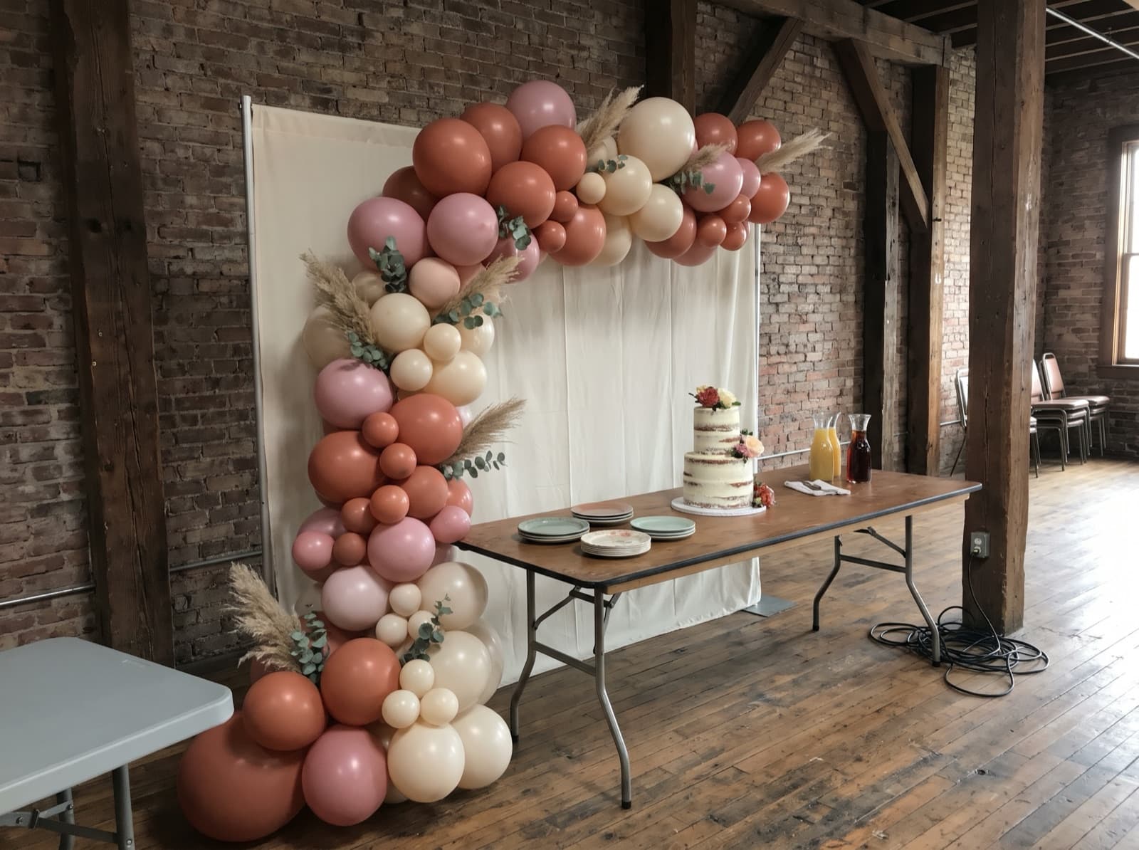 Half balloon arch over a cake table in a brick loft