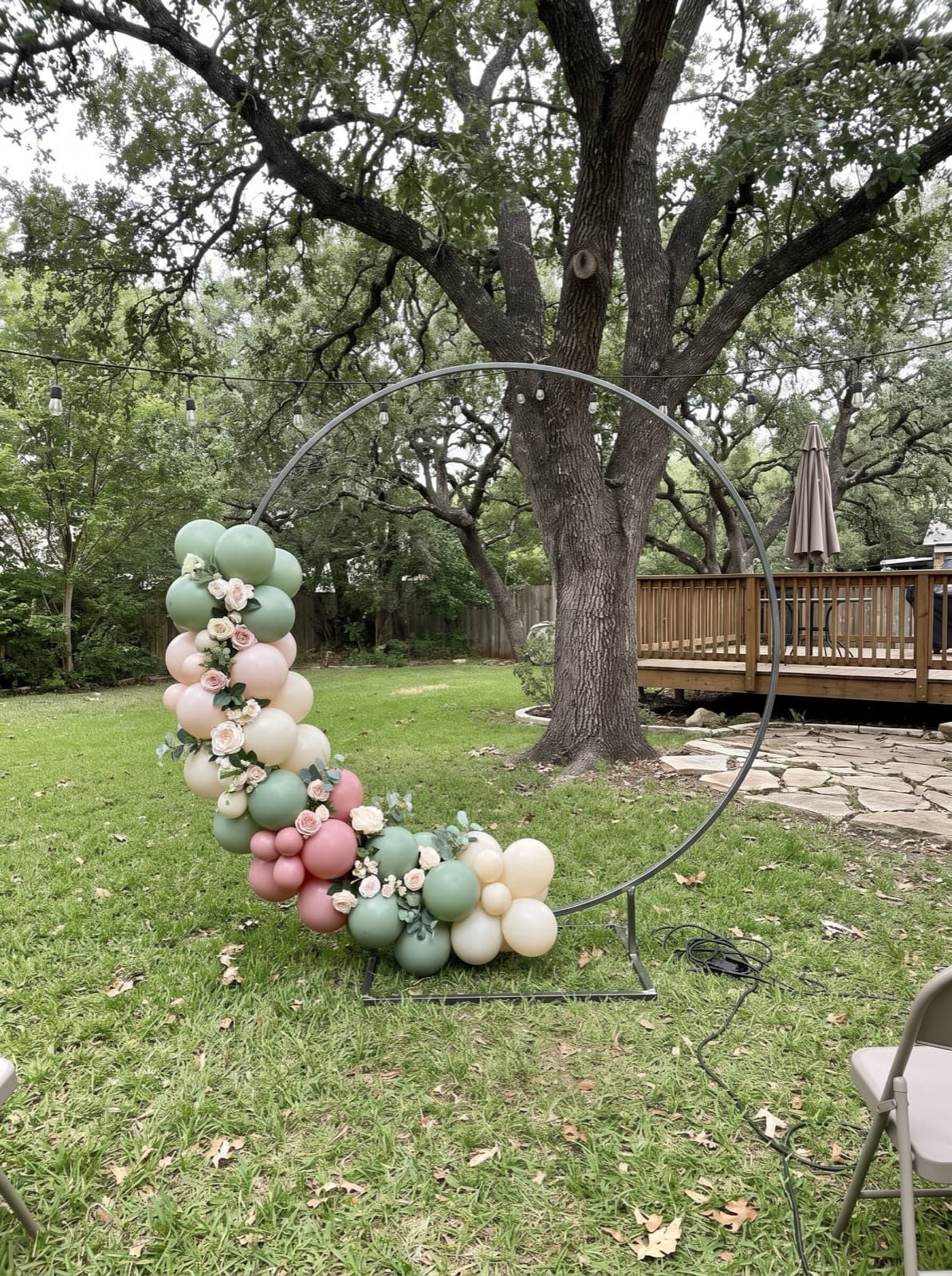Balloon hoop backdrop with florals on a backyard lawn