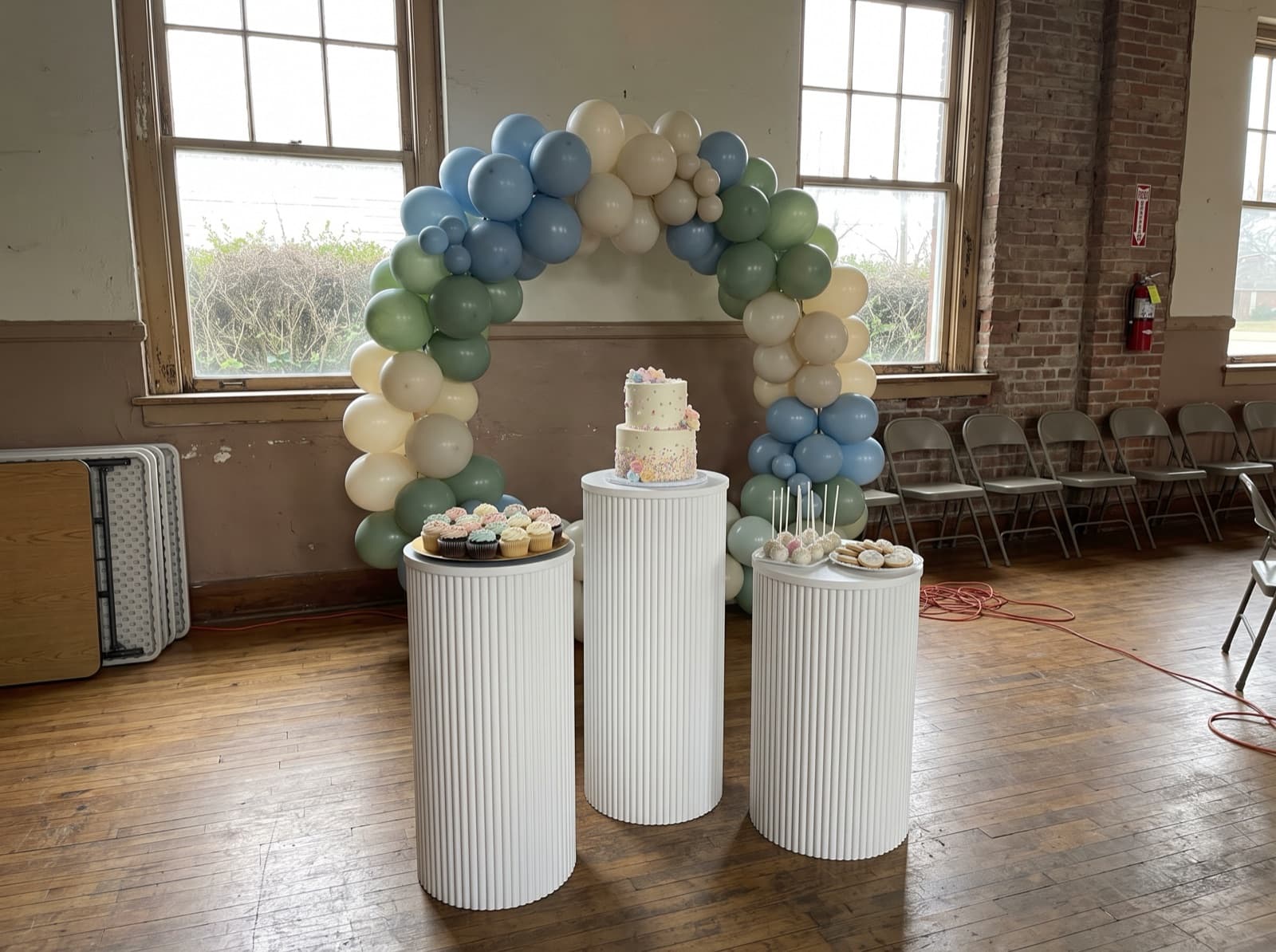 Backdrop with pedestals and a cake table in a parish hall