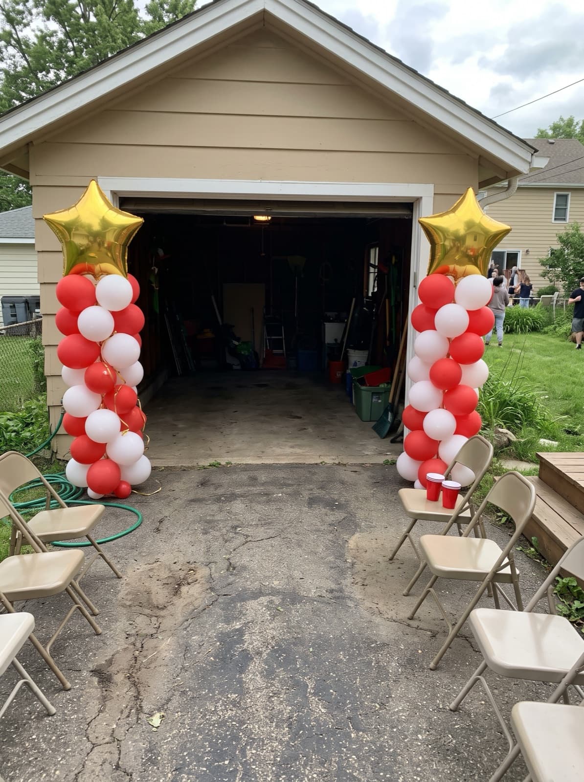Red and white balloon columns with gold star toppers at a graduation party