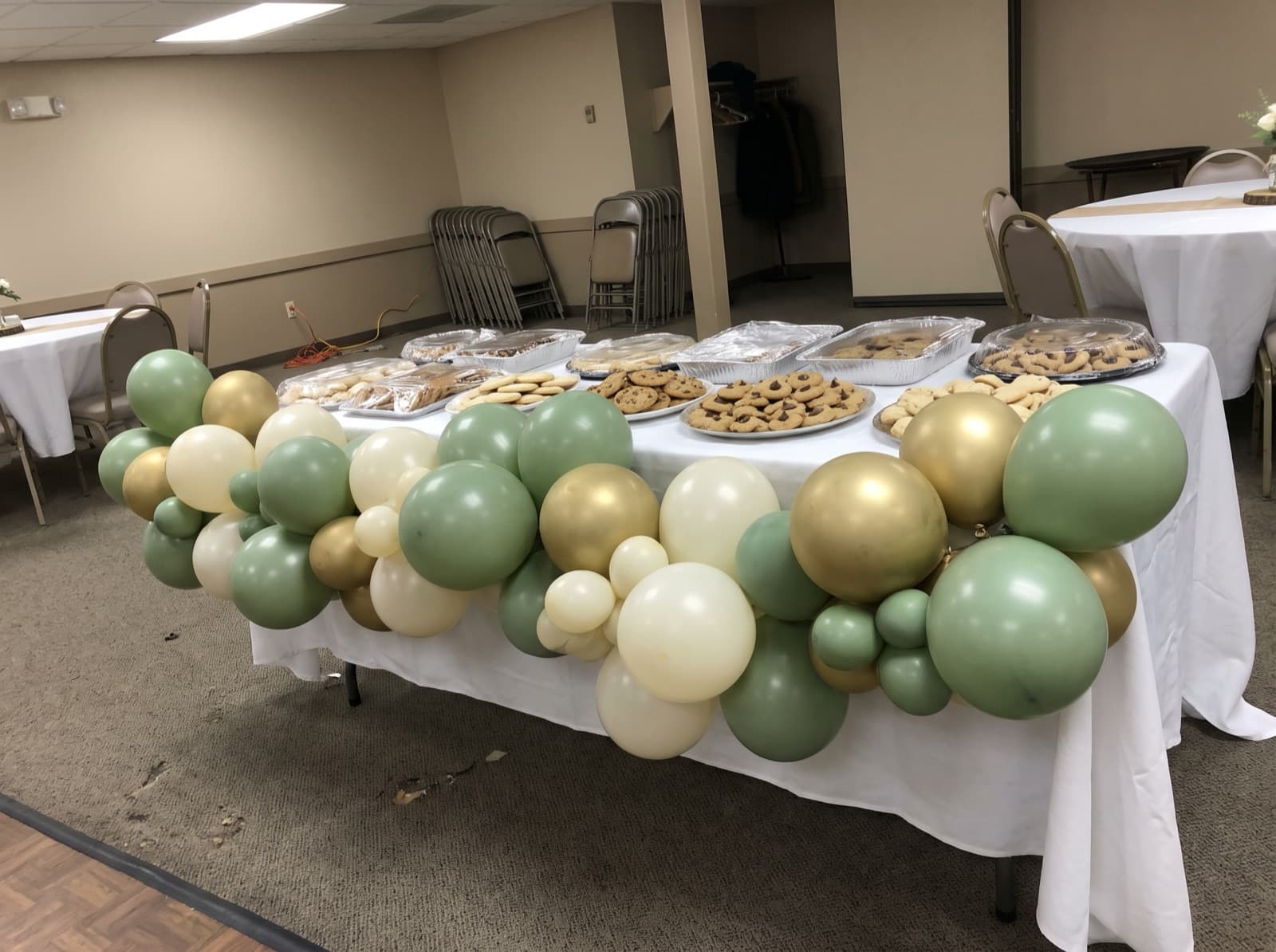 Balloon garland draped across the front of a wedding cookie table