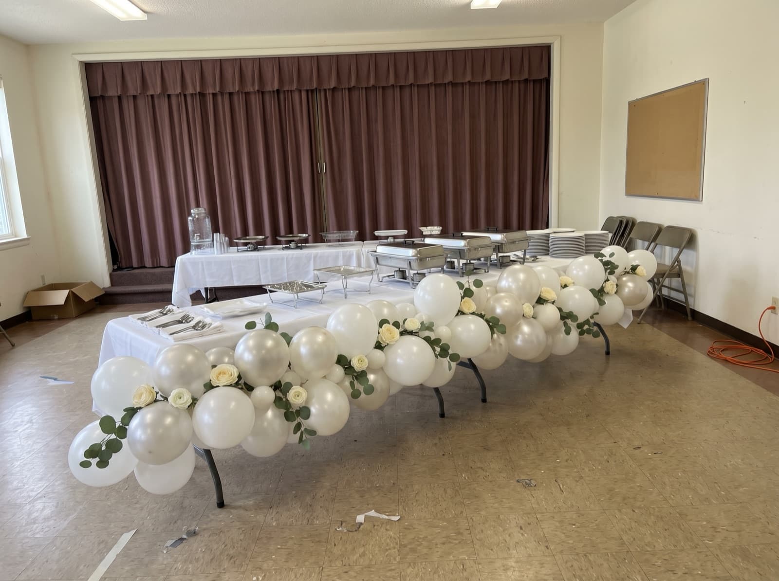 White balloon garland with eucalyptus along a brunch buffet