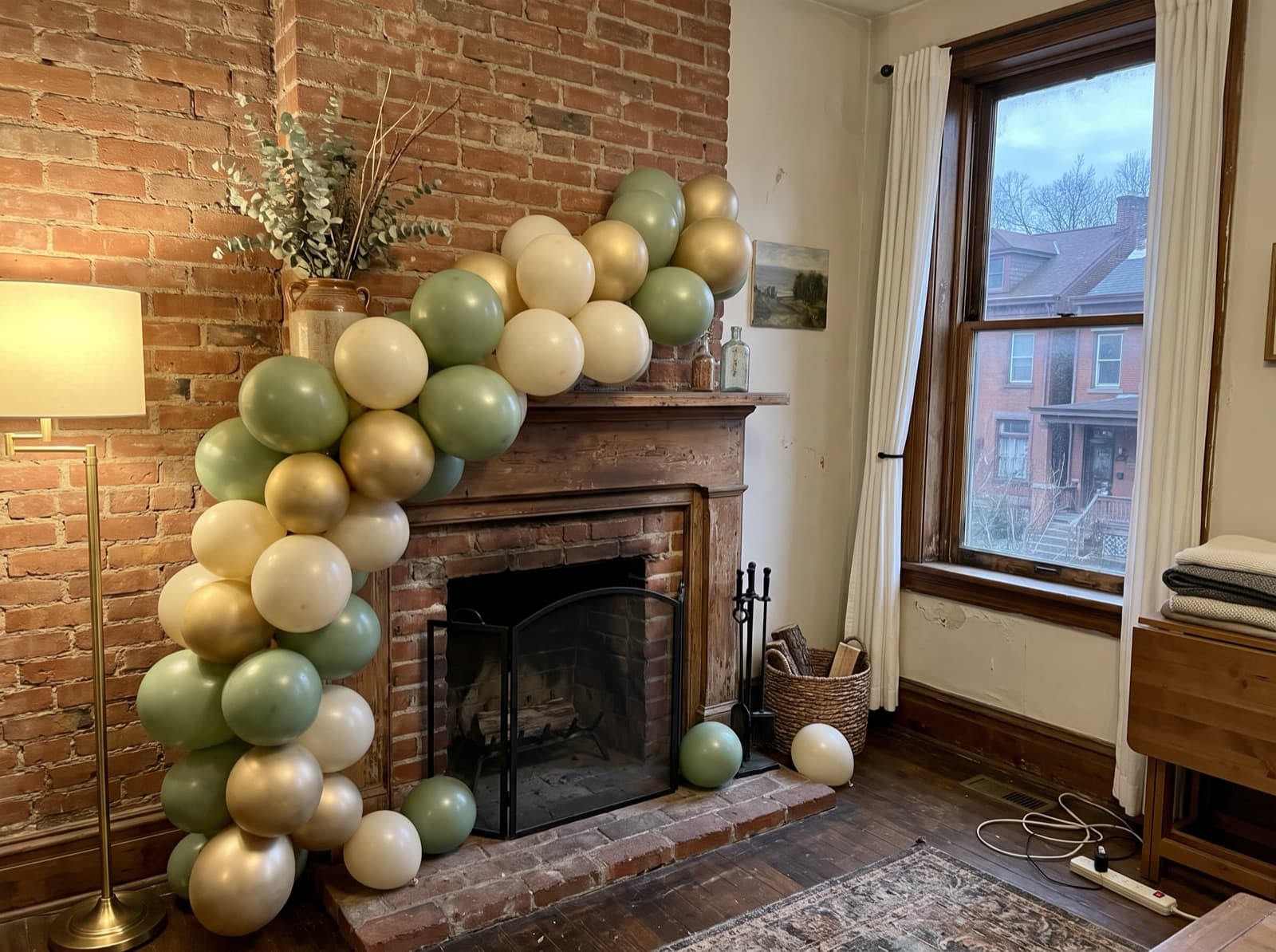 Organic balloon garland in sage, cream and gold along a brick fireplace mantel in a Pittsburgh rowhouse