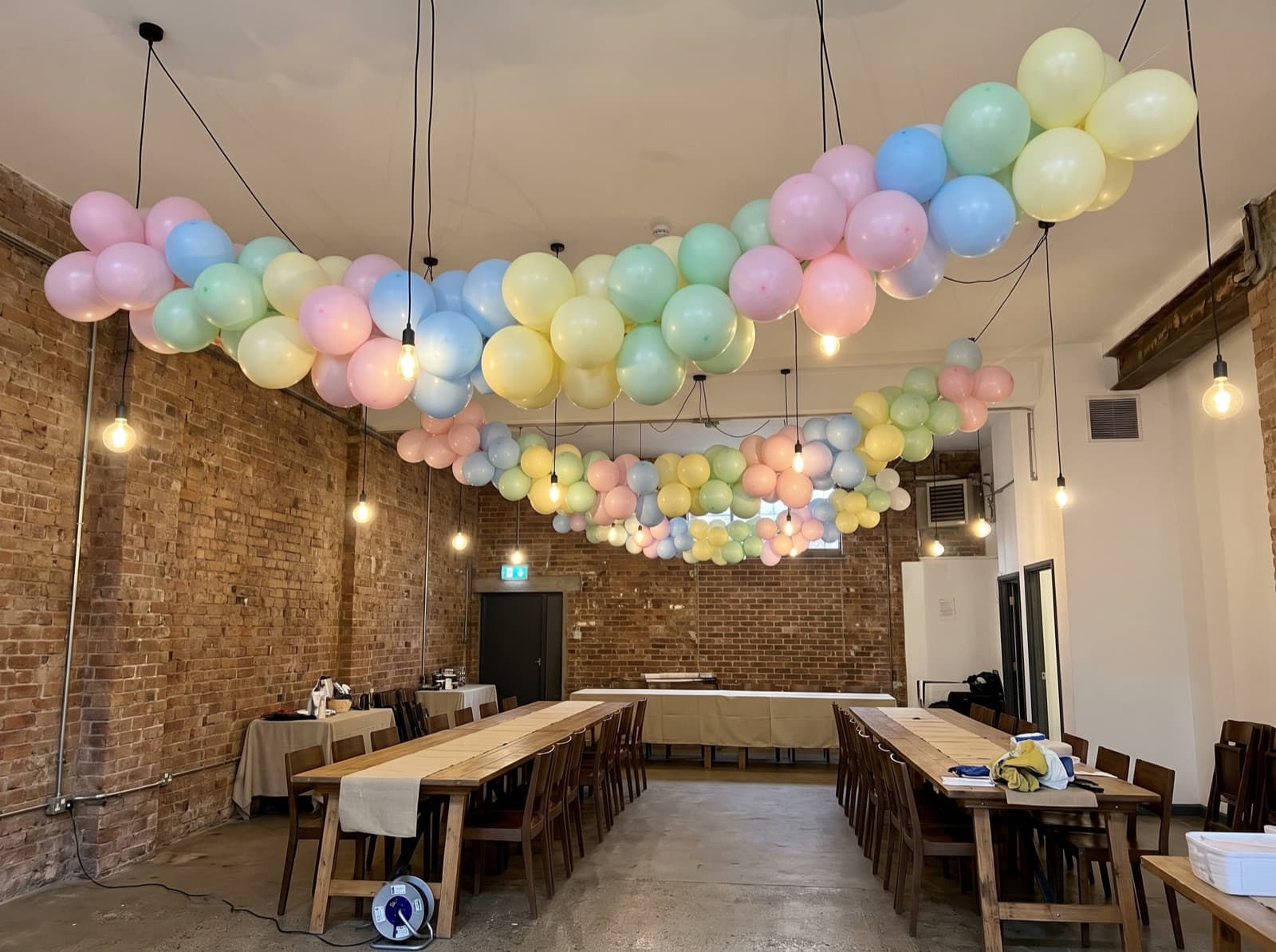 Hanging balloon garland canopy over dining tables