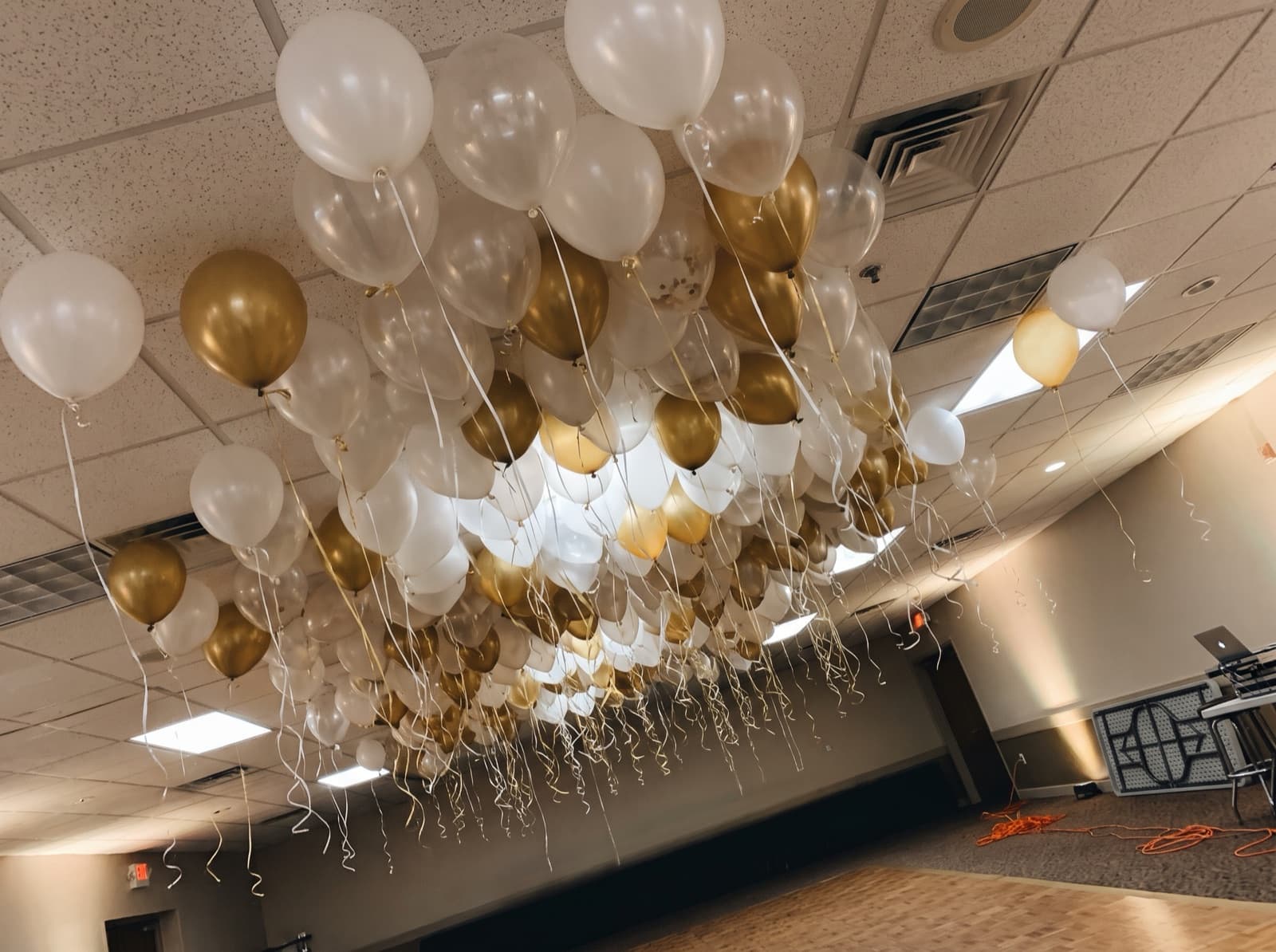 White, clear and gold balloon ceiling floating above a banquet hall dance floor in Pittsburgh