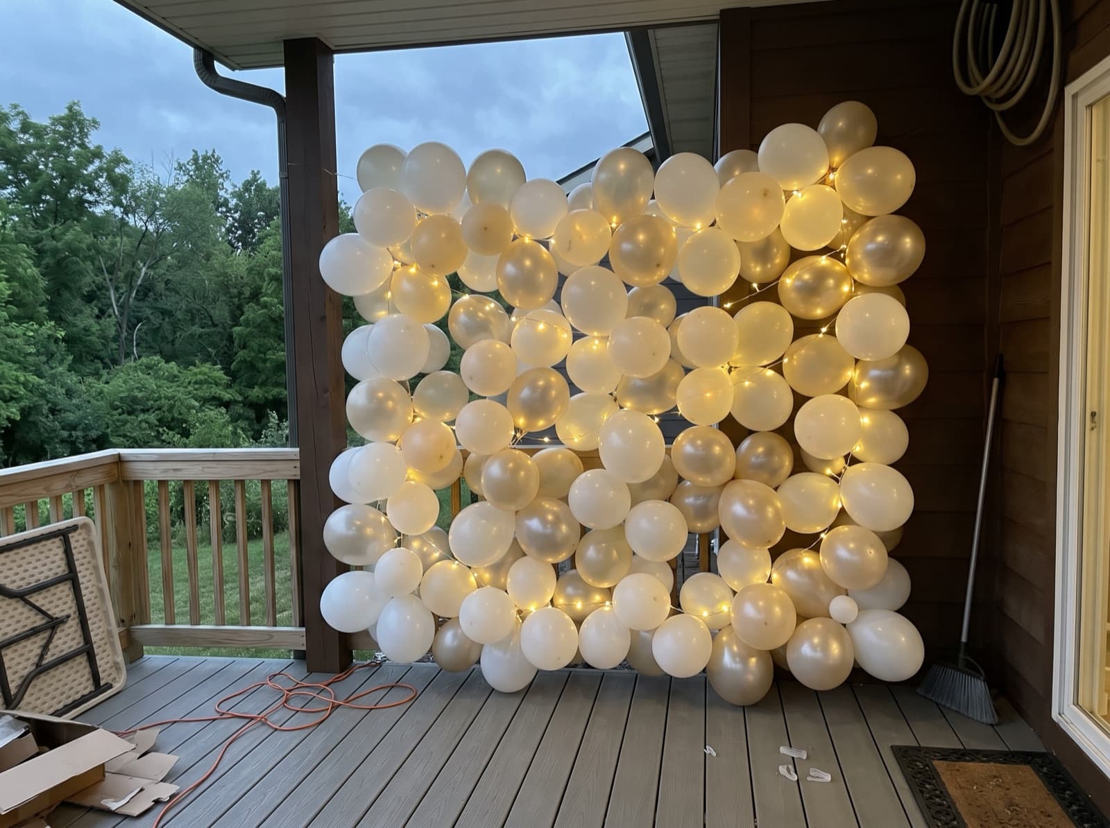 Balloon wall with string lights on a covered deck